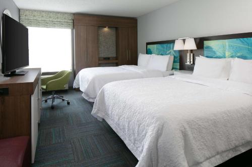 コーラルビルにあるHampton Inn Iowa City/Coralvilleのベッド2台、薄型テレビが備わるホテルルームです。