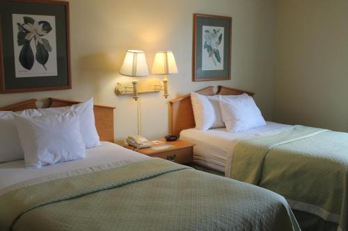 a hotel room with two beds and a phone at Days Inn & Suites by Wyndham Bridgeport - Clarksburg in Bridgeport