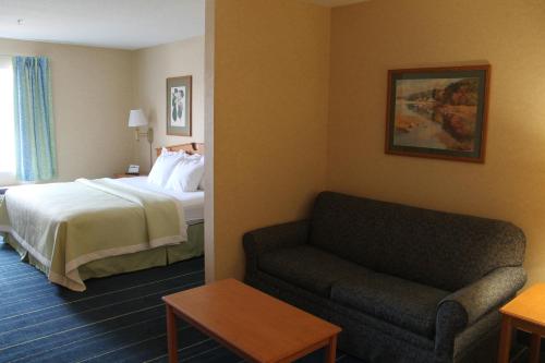 a hotel room with a bed and a couch at Days Inn & Suites by Wyndham Bridgeport - Clarksburg in Bridgeport