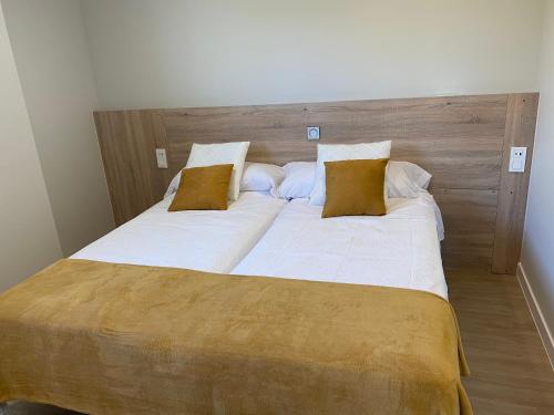 a large bed with white sheets and brown pillows at Apartamentos TARELA Porriño in Porriño