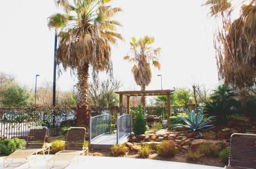 a garden with chairs and a gazebo and palm trees at Hampton Inn & Suites College Station in College Station