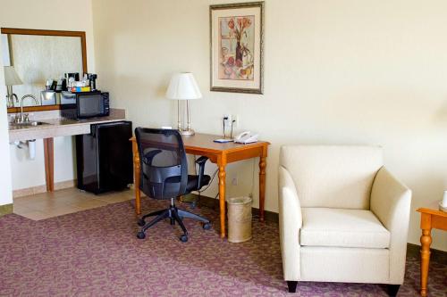 a hotel room with a desk and a chair and a table and a chair at Hampton Inn & Suites College Station in College Station