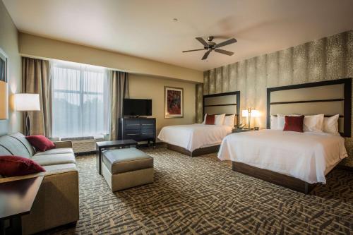 a hotel room with two beds and a couch at Homewood Suites by Hilton Charlotte Ballantyne, NC in Charlotte