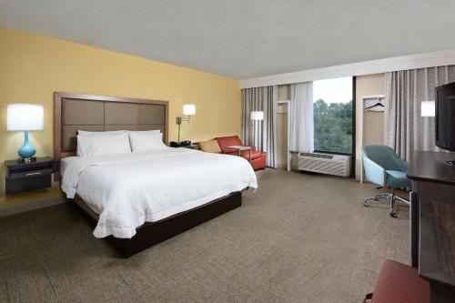 a hotel room with a large bed and a chair at Hampton Inn Charlotte North Lake Norman in Cornelius