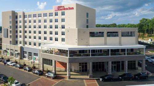 un grand bâtiment blanc avec des voitures garées dans un parking dans l'établissement Hilton Garden Inn Charlotte Waverly, à Charlotte