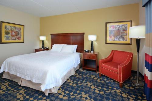 a hotel room with a bed and a red chair at Hampton Inn & Suites Huntersville in Huntersville