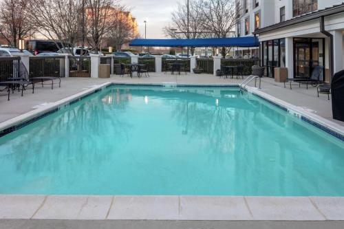 une grande piscine bleue avec des tables et des chaises dans l'établissement Hampton Inn & Suites Concord-Charlotte, à Concord