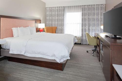 Hampton Inn & Suites Concord-Charlotte في كونكورد: غرفة فندقية بسرير وتلفزيون بشاشة مسطحة