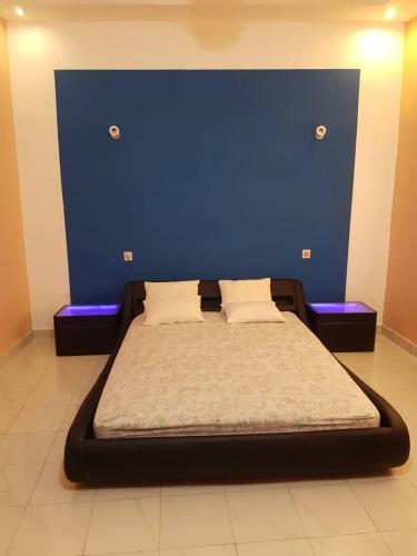 a bed in a room with a blue wall at Superbe appartement en résidence in Cotonou
