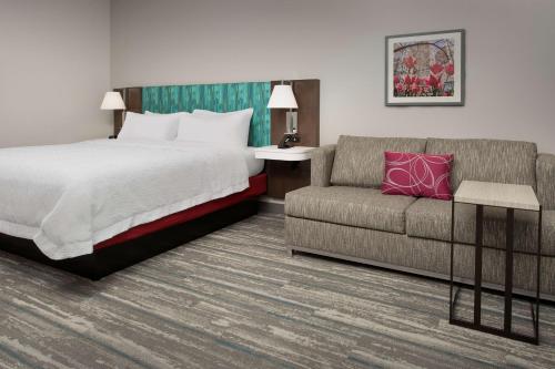 a hotel room with a bed and a couch at Hampton Inn & Suites Charlotte Airport Lake Pointe in Charlotte