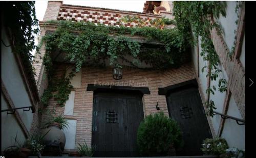 ein Backsteingebäude mit zwei Garagentüren mit Pflanzen in der Unterkunft La hospederia de guadamur in Guadamur