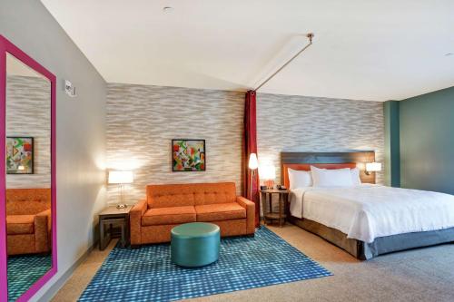 Home2 Suites By Hilton Charlotte Piper Glen في تشارلوت: غرفة نوم بسرير واريكة وكرسي
