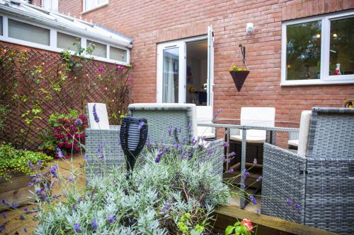 a patio with chairs and a table and flowers at Beautiful House in Stratford upon Avon in Stratford-upon-Avon