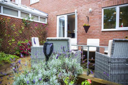 a patio with chairs and a table and flowers at Beautiful House in Stratford upon Avon in Stratford-upon-Avon