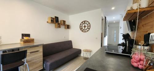 ein Wohnzimmer mit einem Sofa und einer Uhr an der Wand in der Unterkunft Le coin Nature in Amnéville
