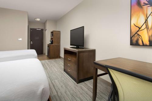 a hotel room with a bed and a desk with a television at Hilton Garden Inn Charlotte Airport in Charlotte