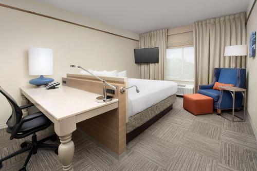 a hotel room with a bed and a desk and chair at Hilton Garden Inn Charlotte Airport in Charlotte