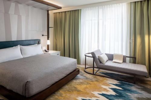 a hotel room with a bed and a chair at Canopy By Hilton Charlotte SouthPark in Charlotte