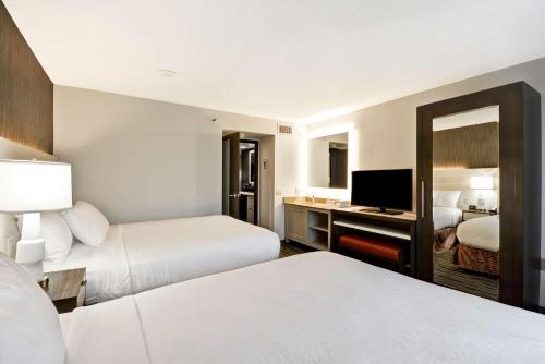 a hotel room with two beds and a television at Embassy Suites Charlotte in Charlotte