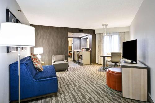 a living room with a blue couch and a tv at Embassy Suites Charlotte in Charlotte