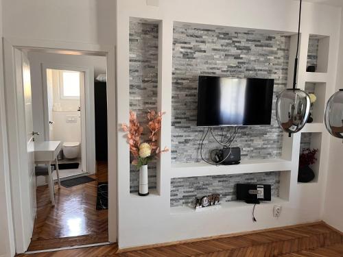 a living room with a tv on a brick wall at Apartman Žanić Ogulin with pool and jacuzzy in Ogulin