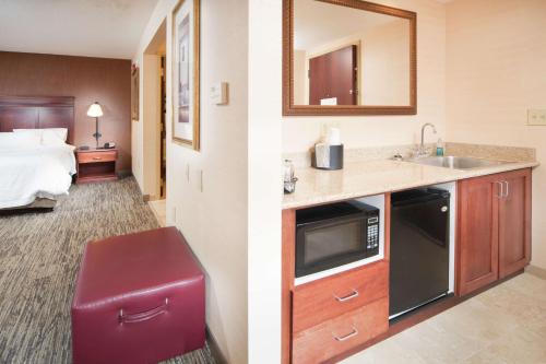 ein Hotelzimmer mit einem Waschbecken und einem Zimmer mit einem Bett in der Unterkunft Hampton Inn & Suites Greensburg in Greensburg
