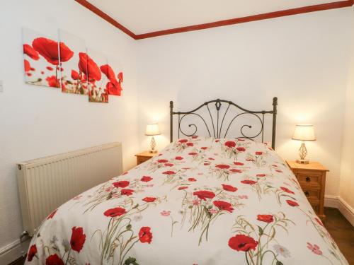a bedroom with a bed with red flowers on it at 5 Woodside Avenue in Rhyl