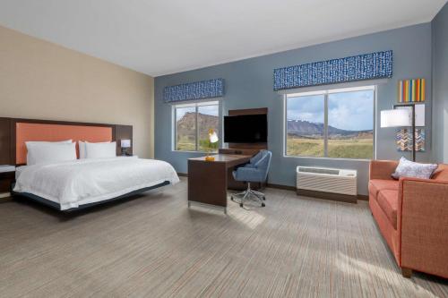 Hampton Inn & Suites Cody, Wy في كودي: غرفه فندقيه بسرير واريكه