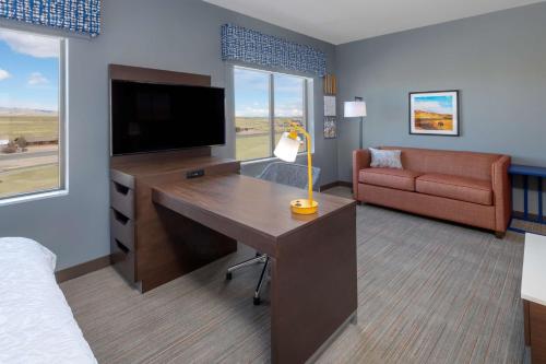 a hotel room with a desk with a television and a couch at Hampton Inn & Suites Cody, Wy in Cody