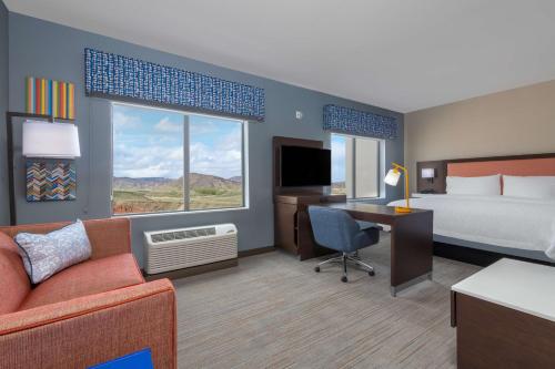 a hotel room with a bed and a desk with a couch at Hampton Inn & Suites Cody, Wy in Cody