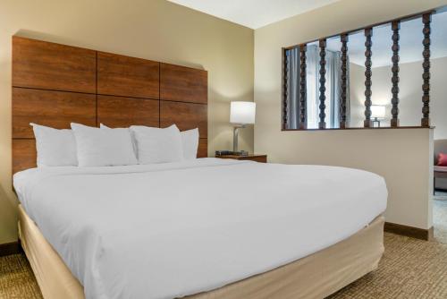 a bedroom with a large white bed with a wooden headboard at Comfort Inn in Manistique