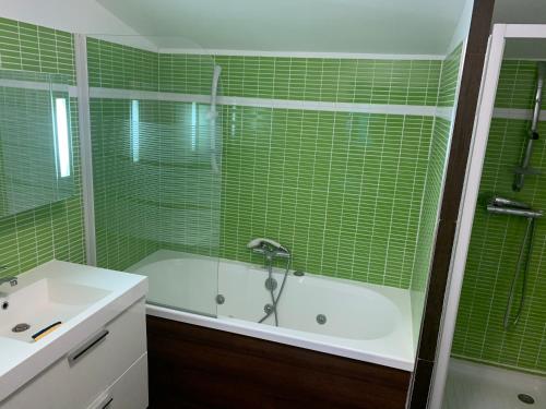 La salle de bains est pourvue de carrelage vert, d'une baignoire et d'un lavabo. dans l'établissement Villa et chalet avec piscine proche Aix & Luberon, à Peyrolles-en-Provence