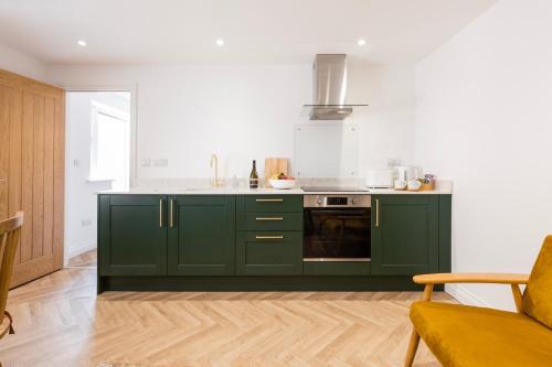 a kitchen with green cabinets and a stove at BRACKEN COTTAGE, The Lanes Cottages, Stokesley in Stokesley