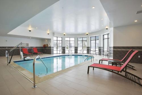 una piscina con sedie rosse e sedie in un edificio di Hampton Inn & Suites - Cincinnati/Kenwood, OH a Cincinnati