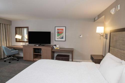 a hotel room with a bed and a desk with a television at Hampton Inn & Suites - Cincinnati/Kenwood, OH in Cincinnati