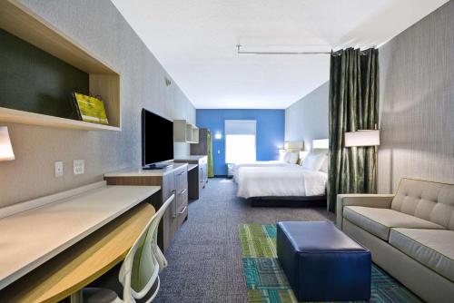 a hotel room with a bed and a couch at Home2 Suites By Hilton Blue Ash Cincinnati in Blue Ash