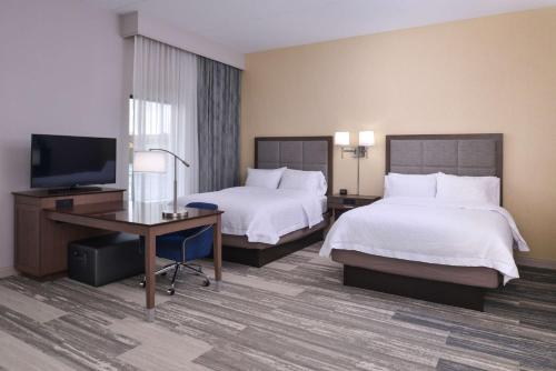 a hotel room with two beds and a desk and a television at Hampton Inn & Suites Cincinnati-Mason, Ohio in Mason