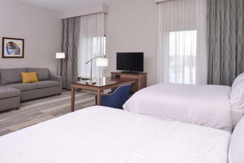 a hotel room with two beds and a couch at Hampton Inn & Suites Cincinnati-Mason, Ohio in Mason