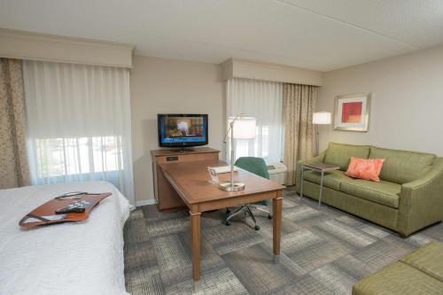 a hotel room with a bed and a couch and a television at Hampton Inn & Suites Cincinnati-Union Centre in West Chester