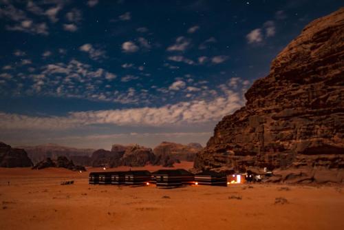 un camping en el desierto por la noche con rocas en Wadi Rum Nature Stars Camp en Wadi Rum