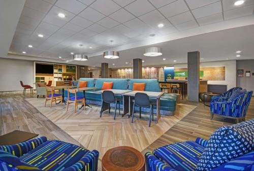 a waiting room with a blue couch and tables and chairs at Home2 Suites By Hilton Springdale Cincinnati in Springdale
