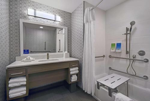 a bathroom with a sink and a mirror and a tub at Home2 Suites By Hilton Springdale Cincinnati in Springdale
