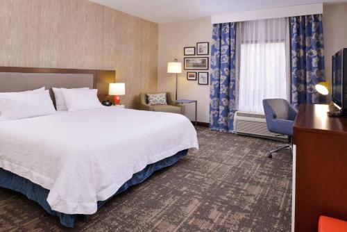 a hotel room with a large bed and a chair at Hampton Inn & Suites Wilmington in Wilmington