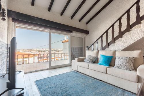 a living room with a couch and a large window at T3 Praia do Baleal in Ferrel