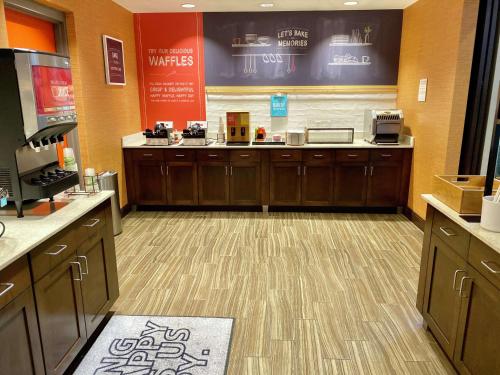 a waiting area of a coffee shop with wooden cabinets at Hampton Inn & Suites - DeLand in DeLand