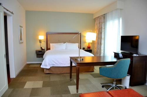 a hotel room with a bed and a desk and a television at Hampton Inn & Suites - DeLand in DeLand