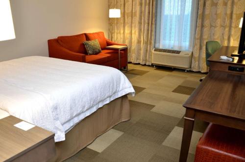 a hotel room with a bed and a chair and a desk at Hampton Inn & Suites - DeLand in DeLand