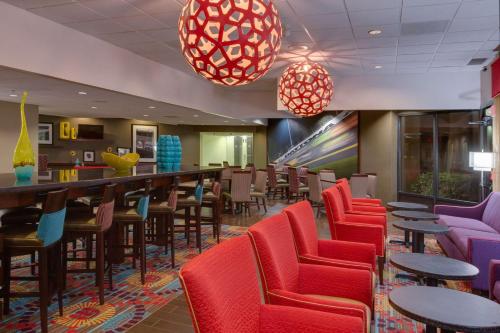 a waiting room with red chairs and a bar at Hampton Inn Daytona Speedway-Airport in Daytona Beach