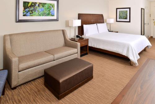 Hilton Garden Inn Addison في أديسون: غرفه فندقيه بسرير واريكه