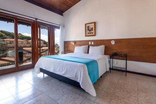 a bedroom with a large bed and a balcony at Hotel Ilha Branca Inn in Búzios